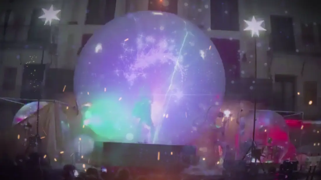 La esfera brillando en la plaza, rodeada de público en plena noche