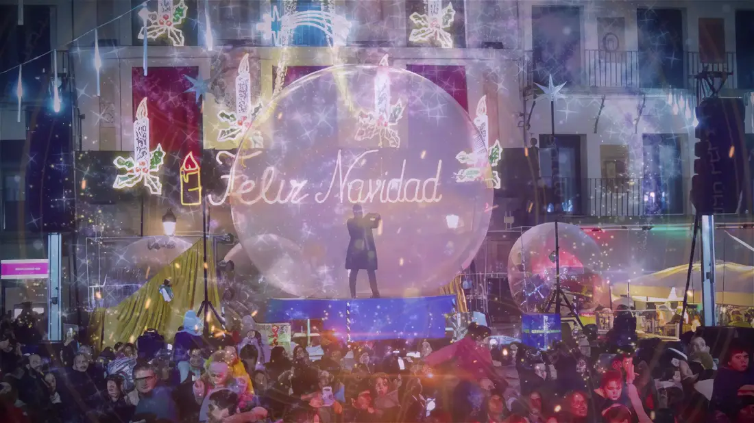 La plaza llena de gente bajo el rótulo luminoso de Feliz Navidad, con la esfera iluminada en el centro