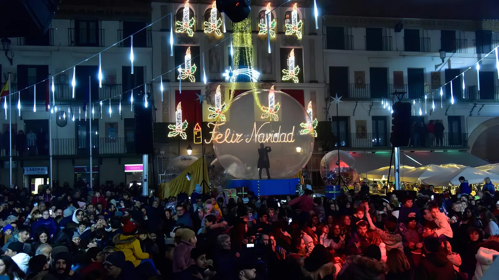 La plaza abarrotada de público con las luces navideñas encendidas y la esfera al fondo