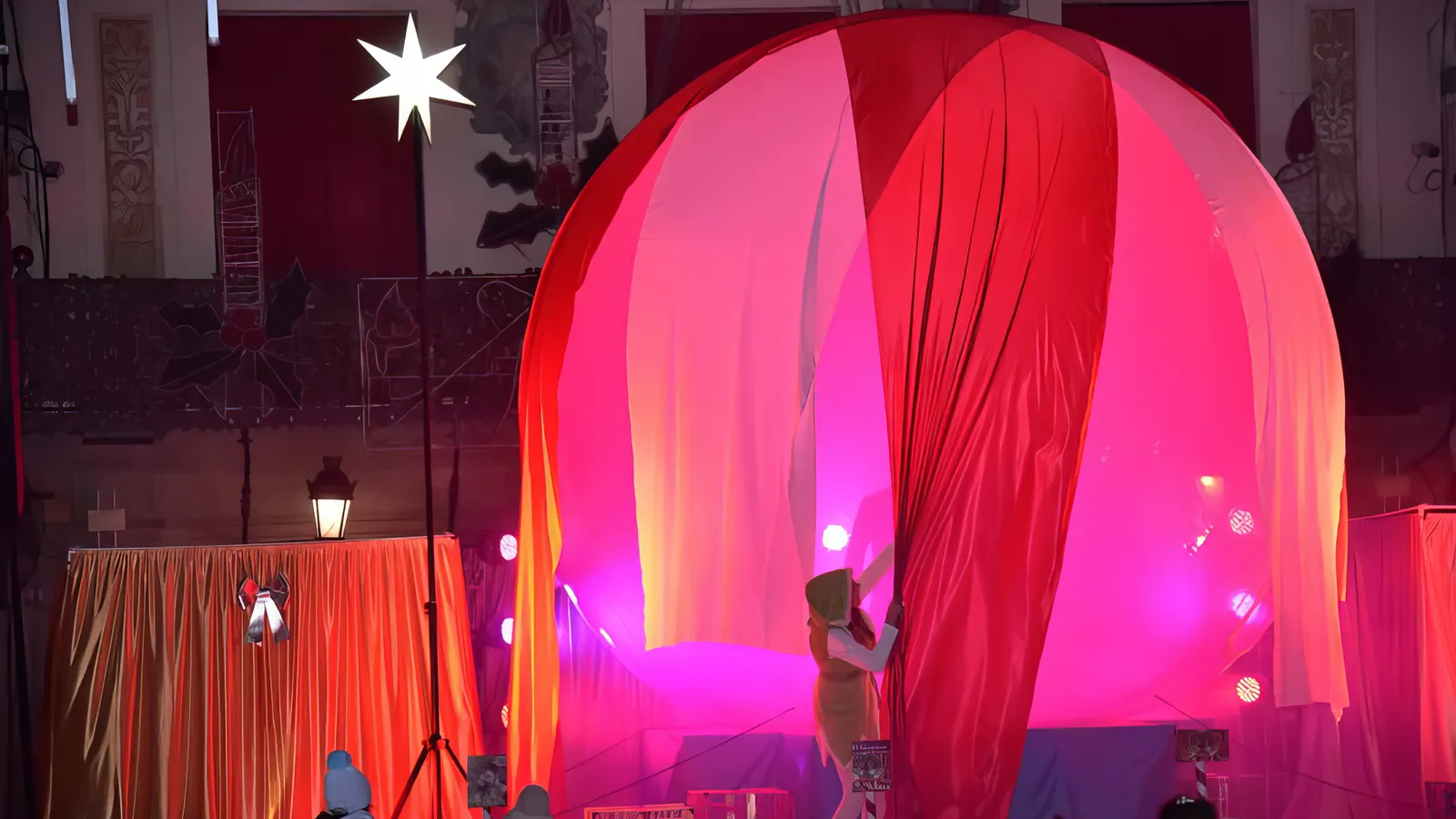 La esfera de cinco metros cubierta con grandes telas rojas en la plaza, junto a una estrella luminosa